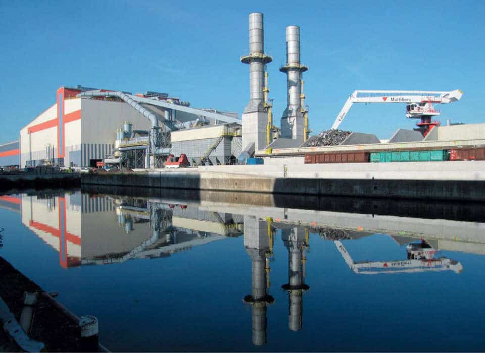 For this milestone project, Siemens VAI was re-sponsible for the overall engineering, erection,and commissioning of the steel works. This included the turnkey supply of a 160-ton electric arc furnace, a 180-ton AOD converter, a twin-180-ton-standladle-treatment station with a common furnace, a single-strand slab caster in addition to auxiliary plants and the dedusting and automation systems. The plant was compactly designed with totally optimized logistics and offers the possibility for future expansion.  Electric arc furnace  Raw materials are transported to the site by either rail or water transport. In the scrap yard different scrap qualities are weighed, loaded in baskets, and then transported to the EAF bay. The EAF itself has an eight-meter diameter, and as such is the largest sized furnace employed in stainless steel making. It is complimented by a 160-MVA transformer which is the most powerful in the world used in stainless steel production. A Level 3 planning system provides the setpoints to the automation system. A process model calculates a cost-optimized melting practice for each single scrap blend.The required flux and alloy additions are accurately calculated and automatically charged to the furnace. Adynamic regulation system maximizes the power in-put and monitors and controls thermal radiation. The economy of operation is further increased through the injection of oxygen and carbon/FeSi through the open slag door by means of a water-cooled lance. This promotes the formation of a foamy slag in the refining phase, which considerably improves the furnace melting efficiency through reduced energy losses. During operations, the EAF is completely enclosed within a dog house to minimize noise and dust emissions.160 tons of liquid stainless steel are tapped into a transfer ladle every 70 minutes on average. Sampling,temperature measurements, and the remaining slag quantity present in the steel is carried out before charging into the AOD.  picture Carinox stainless steelmaking plant  AOD converter  Decarburization of the heat is carried out in an AOD converter. With a diameter of 5.8 meters and a heat size of 180 tons, this is currently the largest converter in the world used in the production of stainless steel. Oxygen and nitrogen or argon are blown into the heat by means of nine under-bath tuyeres installed in the side-walls. Outer annular shroud tuyeres and the application of an intelligent wear-monitoring system protect the inner pipes and maximize their lifetime. The use of a top lance accelerates initial decarburization. The Ugine & ALZ-developed TOP AOD process model allows the exact process targets to be met on the basis of input data from the EAF, raw materials, and additives.The average AOD tap-to-tap time is 70 minutes. During longer waiting times, the temperature of the converter can be maintained using a burner and heat-insula-tion hood which covers the converter opening when the converter is tilted into the horizontal position. The ferro-alloy additive-handling and -charging system is comprised of 28 bins and operates fully auto-matically. It supplies both the EAF and AOD plants. 	  Twin-stand ladle furnace  The heat is transported by crane from the AOD to one of the twin-ladle furnace stands where stirring, compositional and temperature adjustments of the heat can be carried out. The stands also serve as efficient steel buffers in the case of an unexpected production delay. Alloying materials are charged to the ladle furnacefrom a high-level alloy-bin system and each stand is equipped with a multiline wire-injection facility.  picture 160-Ton electric arc furnace Ferro-alloy/additive-handling system 180-Ton AOD converter Twin-station ladle furnace  Dedusting  system Primary emissions from the EAF (1.3 million m3/h) and AOD (1.1 million m3/h) plants are cleaned in a bag-filter station equipped with pulse-jet cleaning. All other plant emissions are filtered in secondary dedusting systems. A clean-gas dust content of less than 5 mg/Nm3 conforms to the latest European regulations. Valuable solid residues can be recycled to the steel making process.  Continuous slab-casting machine  The continuous slab-casting machine is designed to cast more than one million tons of slabs per year at thicknesses from 150 to 250 mm and in widths ranging from 1,000 to 1,650 mm. Two tun dish cars, each equipped with a submerged entry-nozzle-changing device, preheating hoods, and a nozzle preheater, sup-port long casting sequences. A top-feeding dummy-barsystem considerably shortens downtime between two sequences. Featuring the latest mold technology, hy-draulic oscillators, electromagnetic strand stirring,and Smart Segments, the caster is ideally suited to meet all production and quality requirements. Casting speeds of up to 1.4 meters per minute are possible for ferritic and austenitic steel grades. The automation system includes automatic mold-level control, breakout prediction and dynamic cooling models for improved operational safety. A torch-cutting machine cuts the slab to lengths from 5–12 meters. Slab surfaces are ground by one of the four grinding machines. The close proximity of the Carinox plant to the Carlam hot-strip mill and the use of insulation hoods allow the slabs to be hot-charged to the rolling mill.  Leading supplier  With the completion of this project, the Arcelor Mittal group, the largest steel producer in the world today,has acquired a leading position in the stainless steel market. The Ugine & ALZ division in Charleroi, Belgium now supplies approximately 25% of the European market with high-quality stainless steel hot- and cold-rolled products.  Concluding remarks  The large production capacity of the stainless steelworks, coupled with efficient and flexible production scheduling, are key reasons for the economic feasibility of this plant. Advanced process technology, robust and reliable plant equipment, well-trained operational personnel, and the excellent cooperation between the Ugine & ALZ and Siemens VAI project teams were decisive for the overall success of this project.